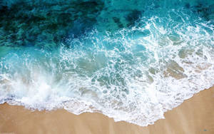 碧綠的海浪在金色沙灘上破碎，泛起白色泡沫。