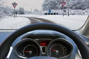 汽車儀表板視角，顯示積雪道路、讓路標誌和積雪的樹木。 — MacBook Pro M2 壁紙