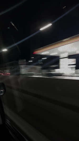 夜間駕車經過加油站，車窗外的燈光掠過。 — 夜晚 壁紙
