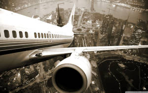 飛機機翼和引擎在夜間飛越發光的城市。 — 伸展台 壁紙