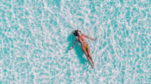 女子在藍綠色海水中仰面漂浮，享受陽光。 — 游泳 壁紙