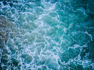 從上方俯瞰，翻騰的海浪帶有白色泡沫和藍綠色海水。 — 海洋藍 壁紙