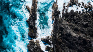 從上方看，碧綠海浪撞擊深色火山懸崖。
