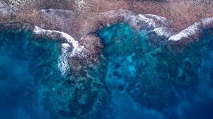 從高空拍攝，碧綠色的海浪在岩石海岸上破碎。 — 百慕達 壁紙