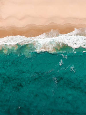 從上方觀看，碧綠色的海浪湧向蜜桃色的沙灘。 — 青色GIF 壁紙