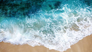 從上方觀看，碧綠色的海浪在金色沙灘上破碎。 — 透明 壁紙