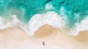 一個人沿著沙灘漫步，碧綠色的海浪翻滾而來。 — 海洋桌面 壁紙