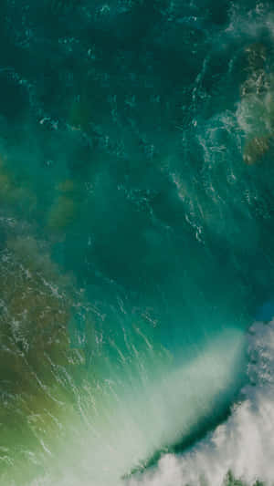 綠松石色的海浪拍打岩石海岸，激起白色泡沫。 — 簡約 iPhone 壁紙