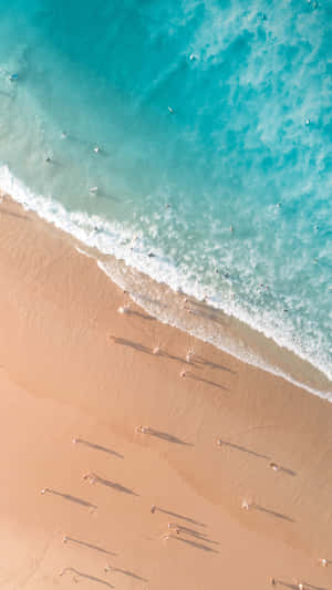 從高空俯瞰，金色沙灘上散落的遊客與綠松石色的海浪。 — 海灘度假 壁紙