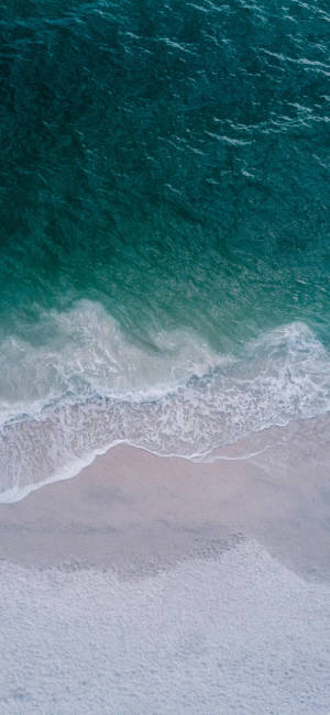 從上方看到綠松石色的海浪與粉色沙灘在海岸線交匯。 — 波浪 壁紙
