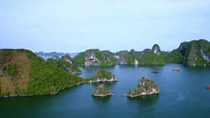 鬱鬱蔥蔥的喀斯特島嶼從平靜的藍色海水中升起，天空晴朗。 — 藍天 壁紙