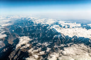 積雪的山峰在明亮的藍天下聳立於雲海之上。