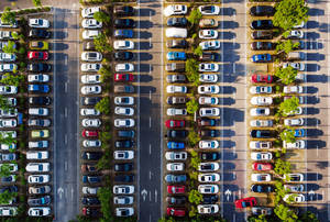從正上方俯瞰停車場，可見一排排色彩繽紛的汽車和綠樹。 — 桌面 壁紙