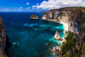 熱帶海灘海灣，擁有碧綠色的海水和被綠色植物環繞的岩石懸崖。 — MacBook Pro 壁紙