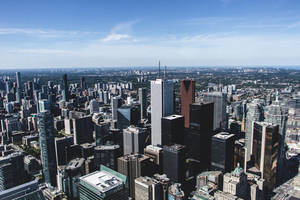 從高空俯瞰密集的現代城市，高聳的摩天大樓和清澈的藍天。 — 城市 壁紙