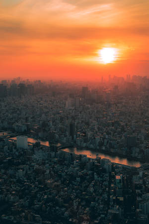 夕陽下的密集城市，河流蜿蜒穿過建築物。 — 日本 壁紙