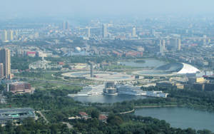 從高空俯瞰現代城市，有湖泊和綠地，天空朦朧。 — 中國 壁紙