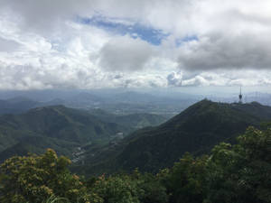 山脊，遠處可見城市天際線，在多雲的天空下。 — 唐人街 壁紙