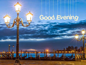 復古路燈在黃昏時照亮海濱，天空懸掛著「Good Evening」。 — 晚安 壁紙