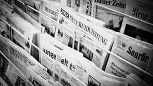報攤報架上的一疊德國報紙，可見標題。 — Old Paper 壁紙