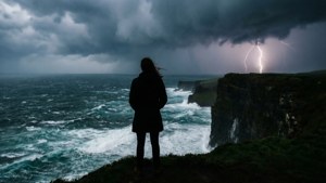 人站在懸崖上觀看閃電劃過波濤洶湧的海面。 — 憂鬱 GIF 壁紙
