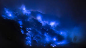 夜間，生物發光波浪在深色火山岩上發出藍色光芒。 — 藍色火焰 壁紙