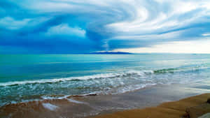 暴風雲在海灘上空旋轉，碧綠的海浪翻滾而來。 — 海灘桌面 壁紙