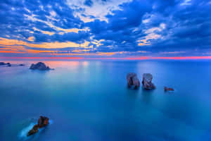 日落時分平靜的海洋，岩石小島在色彩繽紛的天空下 — 日落 壁紙
