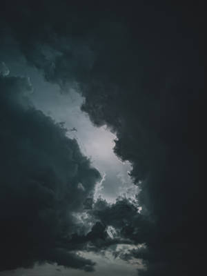 黑暗的暴風雲散開，顯示出明亮的天空。 — 簡約暗黑美學 壁紙
