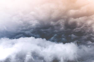 金色光芒下的深灰色和白色形態的戲劇性暴風雲。 — 凋零風暴 壁紙