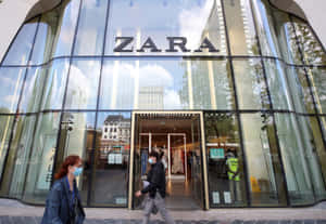 戴著口罩的行人經過一間有大玻璃窗的Zara服裝店。 — Zara 壁紙