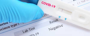 戴著手套的手在實驗室報告上拿著陰性的COVID-19測試條。 — 醫療 壁紙