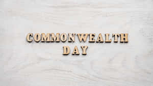 在淺色紋理背景上拼寫 Commonwealth Day 的木製字母。 — 彩虹旗 壁紙