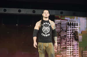 摔角手 Baron Corbin 在舞台上穿著黑色 T 恤和工裝褲。 — WWE GIF 壁紙