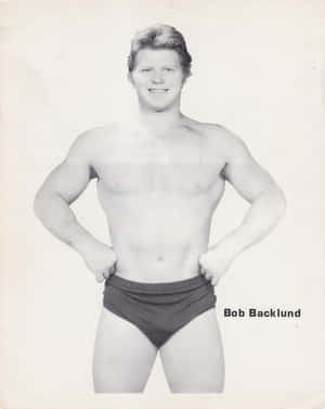摔角手 Bob Backlund 穿著短褲，在復古照片中雙手叉腰擺姿勢。 — 4:5 壁紙