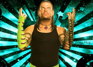 摔角手 Jeff Hardy 帶有刺青和綠色手臂繃帶，在藍綠色星爆背景前。 — 湯姆·哈迪 壁紙