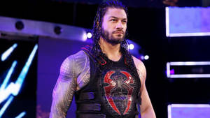 摔角手 Roman Reigns 身穿帶有紅色蜘蛛標誌的黑色背心，在紫色燈光下。 — 羅曼·雷恩斯 壁紙