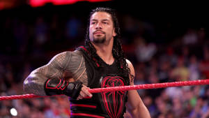 摔角手 Roman Reigns 在場館中緊握擂台繩索，身後有觀眾。 — 羅曼·雷恩斯 壁紙