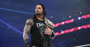 Roman Reigns 在摔角擂台上於場館燈光下手持冠軍腰帶。 — 羅曼·雷恩斯 壁紙