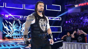 摔角選手 Roman Reigns 走過燈光明亮的場館，周圍有歡呼的粉絲。 — 羅曼·雷恩斯 壁紙