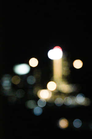 在城市環境中，黑暗夜空下柔和發光的散景燈光。 — 簡約暗黑美學 壁紙