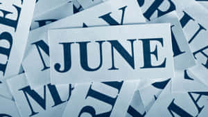 一堆白色卡片，上面有海軍藍字母拼出 JUNE — 六月 壁紙