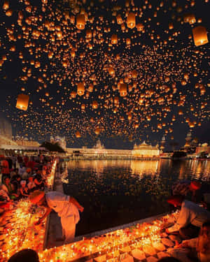 人群在夜間在寺廟上空釋放天燈，水邊有燭光。 — 綠光戰警 壁紙