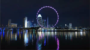 夜晚的新加坡天際線，摩天輪亮起，城市燈光倒映在水中。 — 城市風景 壁紙