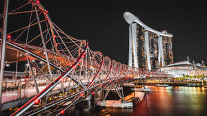 螺旋橋在夜間亮燈，背景為濱海灣金沙 — 塔橋 壁紙