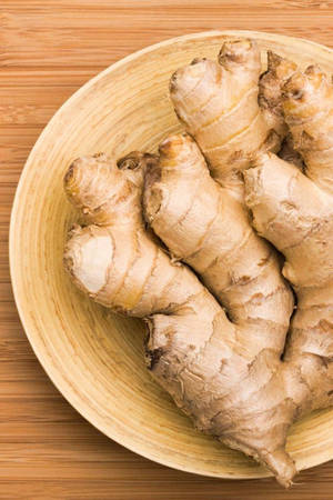 竹製表面上的木碗裡的新鮮生薑根 — 蔬菜 壁紙