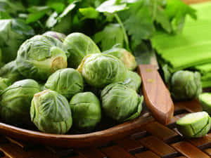 新鮮球芽甘藍在木碗中，配以歐芹和芹菜，放在編織墊上。 — 4:3 壁紙