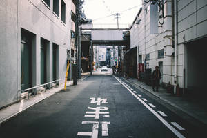 狹窄的日本街道，有行人和天橋下的白色道路標記。 — 街頭 壁紙