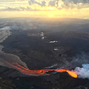 熔岩河流經黑暗的火山景觀，在金色日落天空下。 — 自然 壁紙