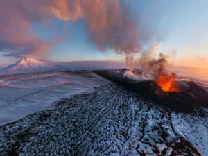 在色彩繽紛的日落天空下，白雪覆蓋的火山噴出熔岩和火山灰。 — 山景 壁紙